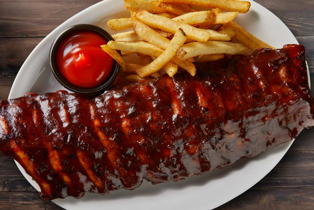 a plate of bbq baby back ribs with fries and ketchup