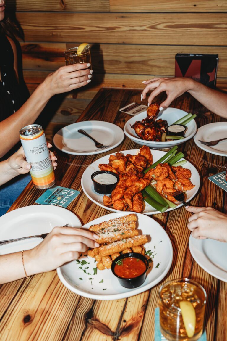 plates of Zingers, mozzarella Sticks and Wings while friends are enjoying drinks