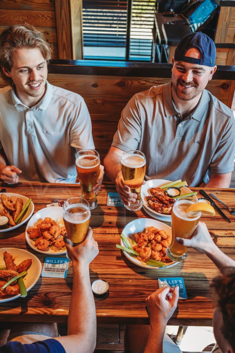 4 guys hang out with beers and chicken wings