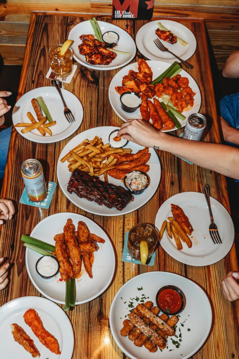 a plate spread of different plates with mozzarella sticks, bbq ribs, wings and zingers